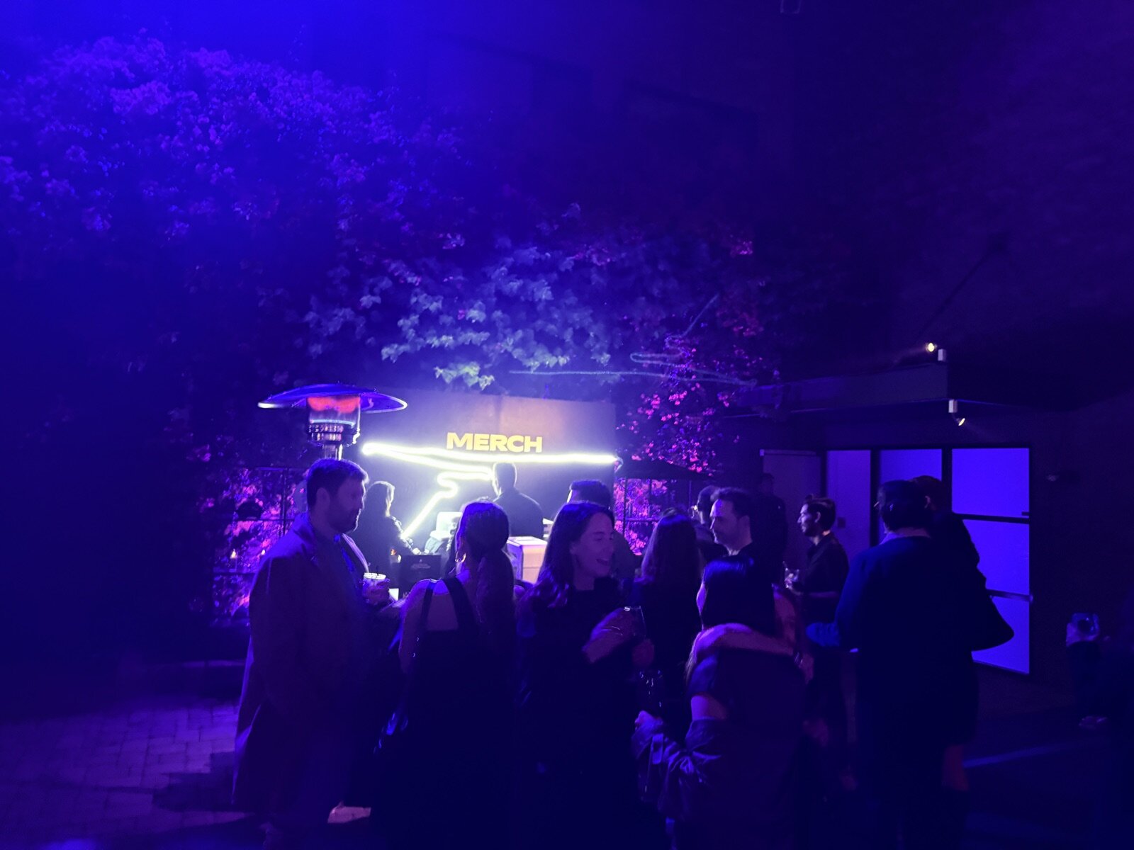 Guests gathered outside a glowing activation booth at a nighttime brand event