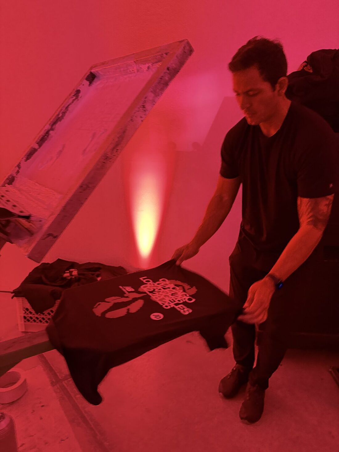 Operator inspecting a finished dark garment under station lighting