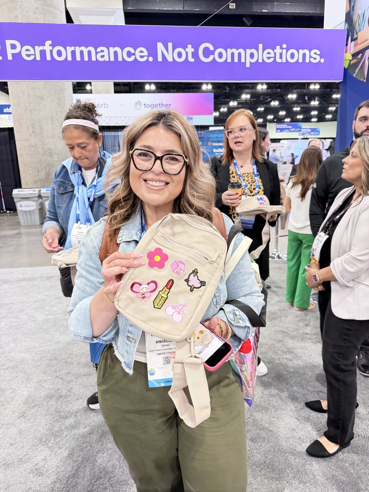 Conference attendee showing off a canvas tote personalized with patches on a trade show floor